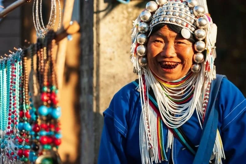 An Akha woman in traditional clothing selling traditional handmade Akha souvenirs.