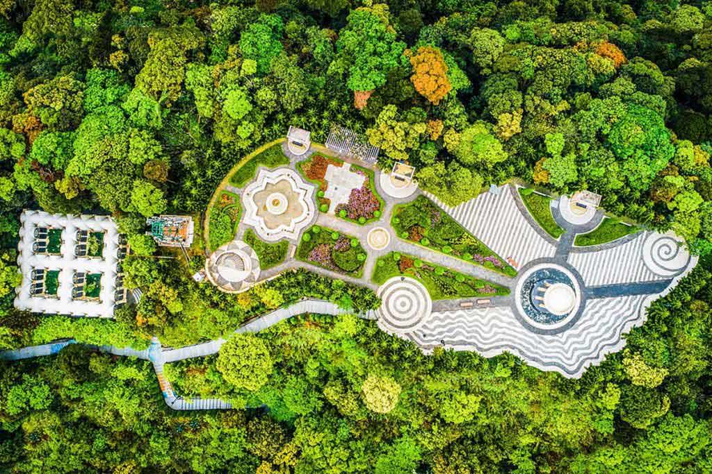 Aerial view of the Le Jardin d’Amour flower gardens at Ba Na Hills surrounded by lush forest.