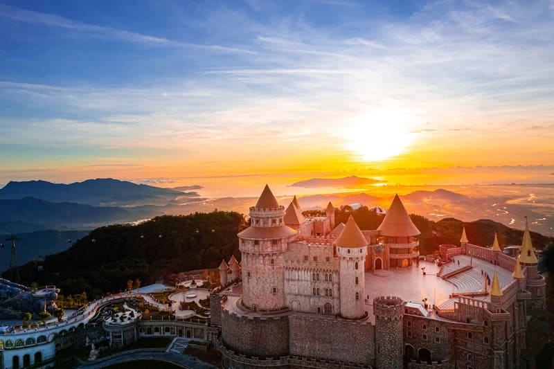 Aerial view of Ba Na Hills at sunrise with golden light shining over the French Village architecture