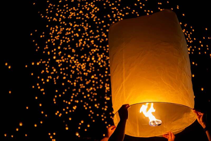 A myriad of lanterns soaring into the night sky, illuminating the starry night at Thailand's beautiful Yi Peng Festival