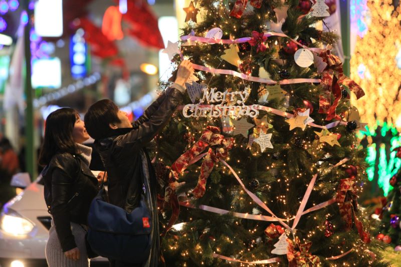 Two Asians decorate a Christmas tree