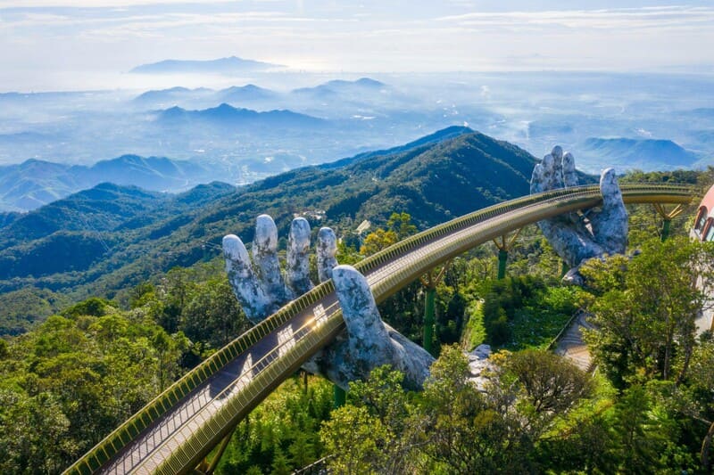 Aerial view of the iconic Golden Bridge Da Nang curving through lush mountains in Ba Na Hills