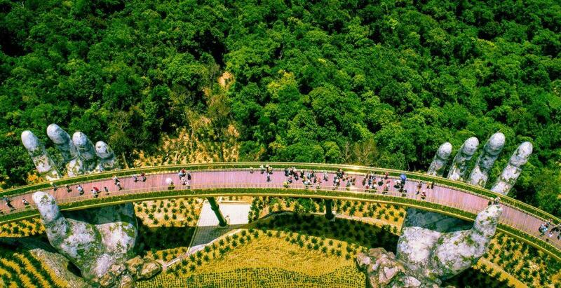 Overhead shot of the Golden Bridge with tourists walking between giant stone hands
