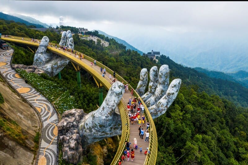 Tourists walking across the Golden Bridge held by giant hands in Ba Na Hills