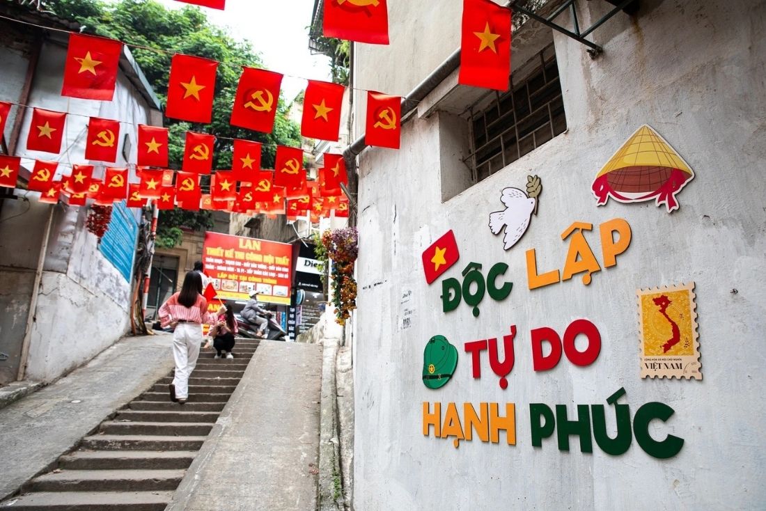 A wall in a residential neighborhood is decorated with the national motto: Independence - Freedom - Happiness